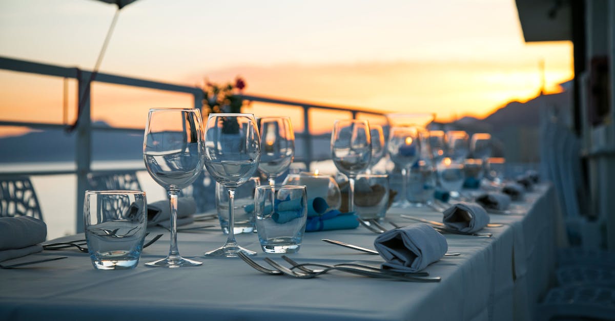 A beautifully set long table at sunset, overlooking the seaside, perfect for outdoor dining.
