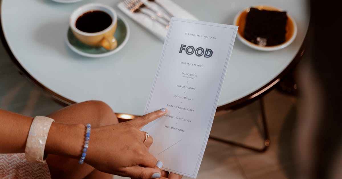 Hands holding a menu, selecting options at a cozy cafe with coffee and dessert on the table.