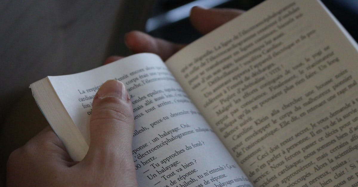 A person reading a book, focusing on the text and hands, in a cozy indoor setting.