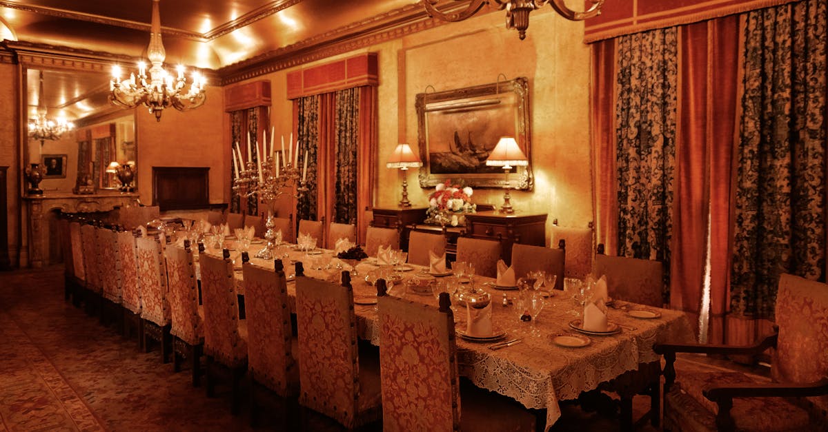 A lavishly decorated dining room with ornate chandeliers and a long banquet table set for a luxury dinner.