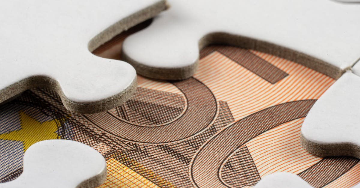 Detailed macro view of white puzzle pieces partially covering a Euro banknote.