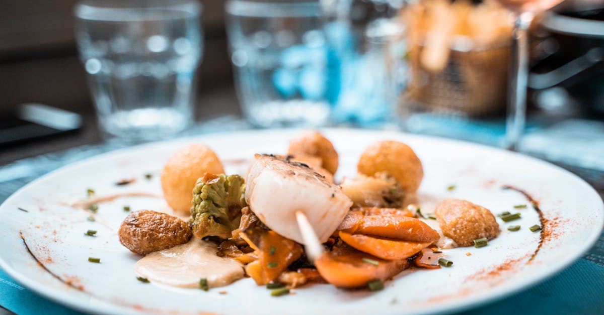 Beautifully plated scallop dish with vegetables and fries in a French restaurant setting.