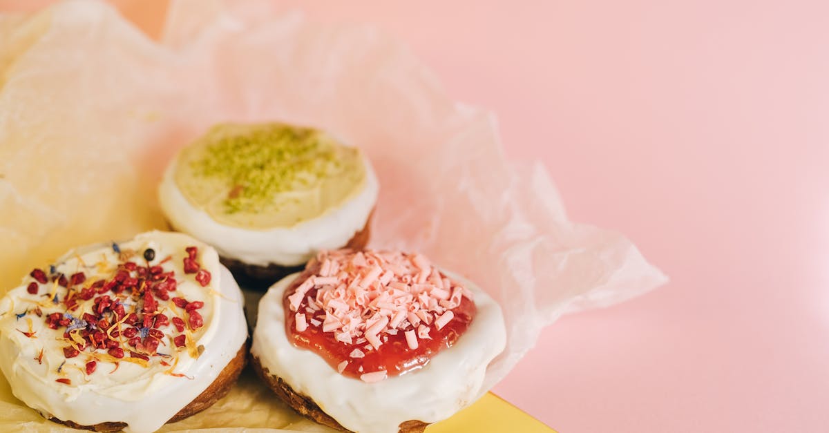 Delicious assorted cronuts with colorful toppings on parchment paper over a pastel background.