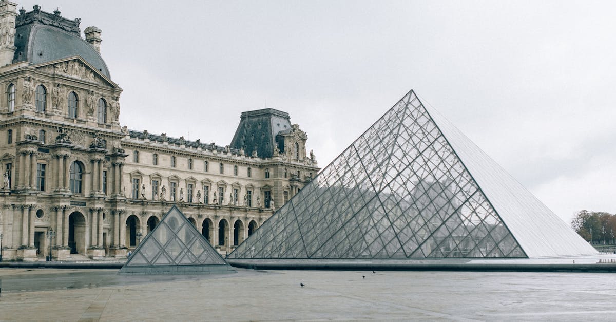 The iconic Louvre Museum with its glass pyramid on a cloudy day in Paris, France.