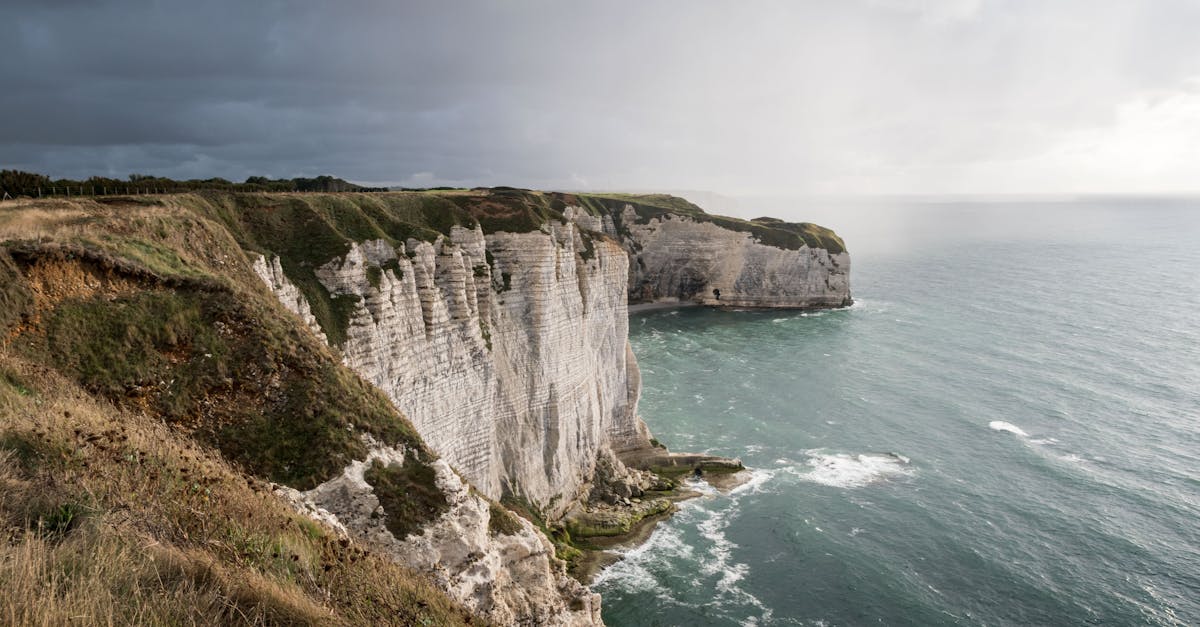 Majestic cliffs at Étretat, Normandy, France, under a dramatic cloudy sky.