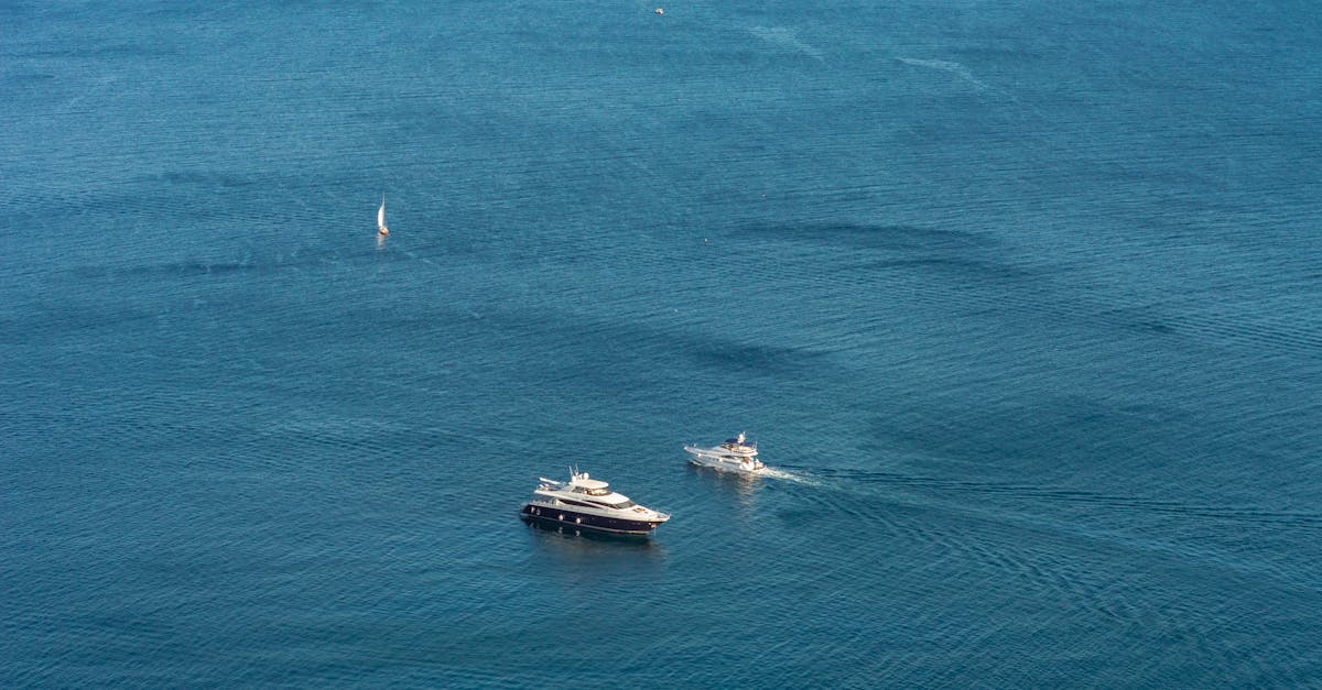 A stunning aerial view of yachts and a sailboat navigating the expansive blue sea, showcasing nautical adventure.
