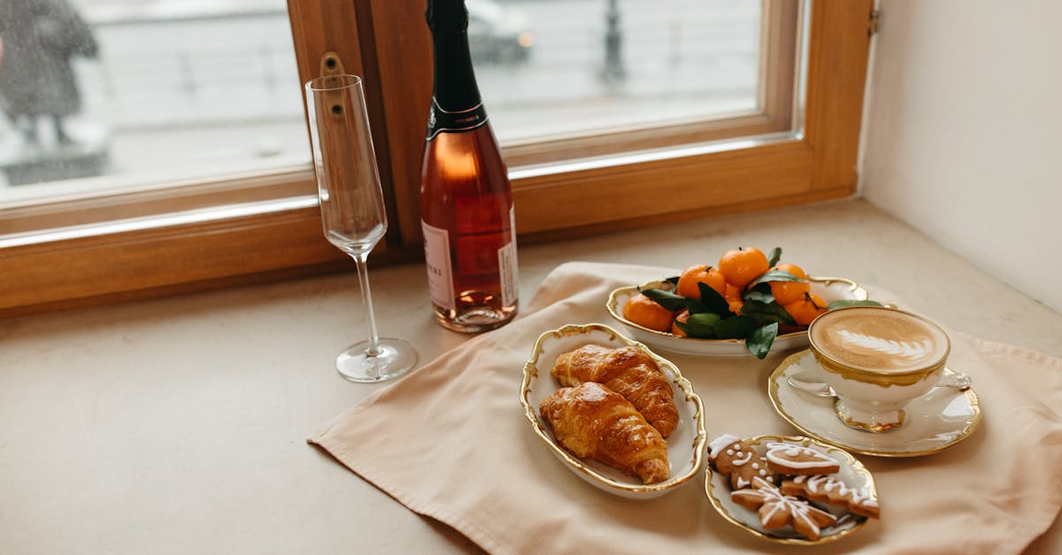 Elegant breakfast with croissants, coffee, and champagne by a window with a winter view.