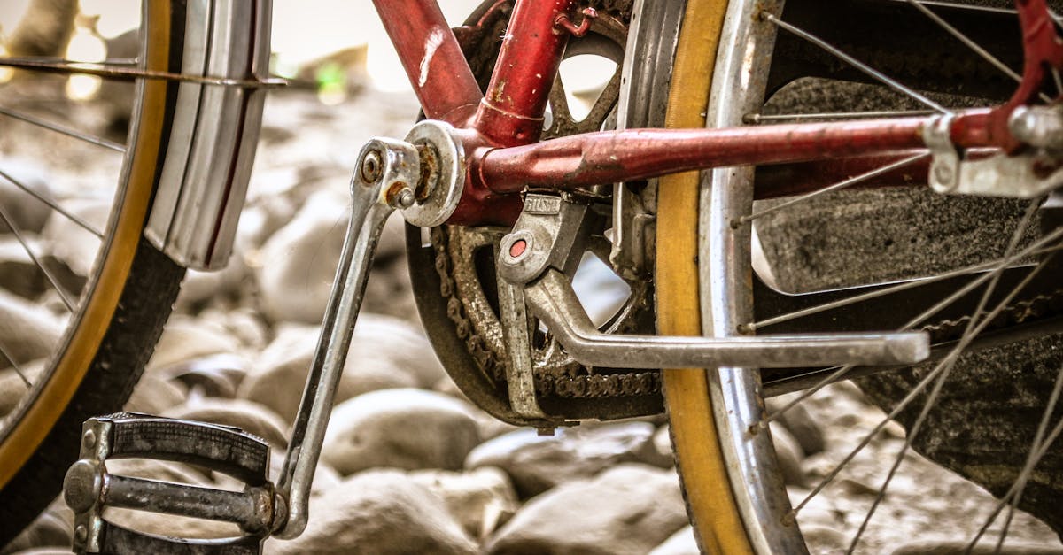 Detailed close-up of a vintage bicycle pedal and chain, parked on pebbles.