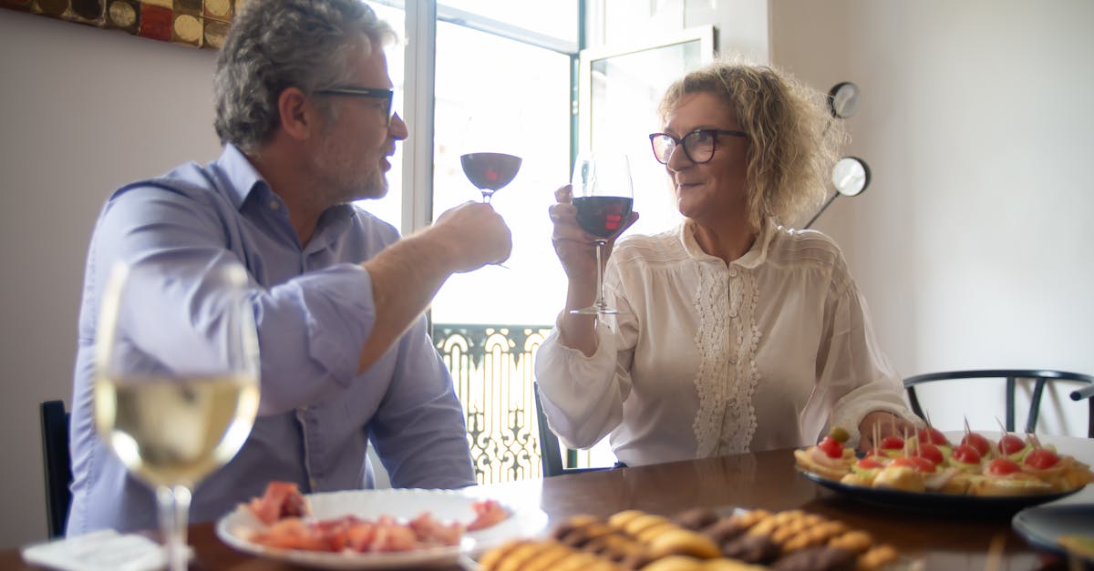 A couple enjoys snacks and red wine in a cozy indoor setting, perfect for a celebration.
