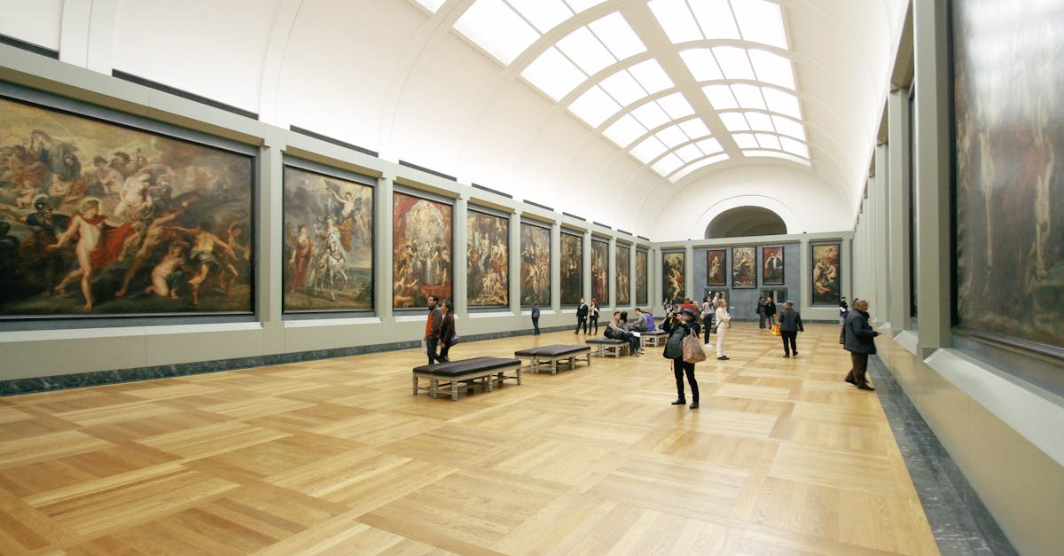 A wide view of a museum hall showcasing famous paintings and visitors exploring the art.