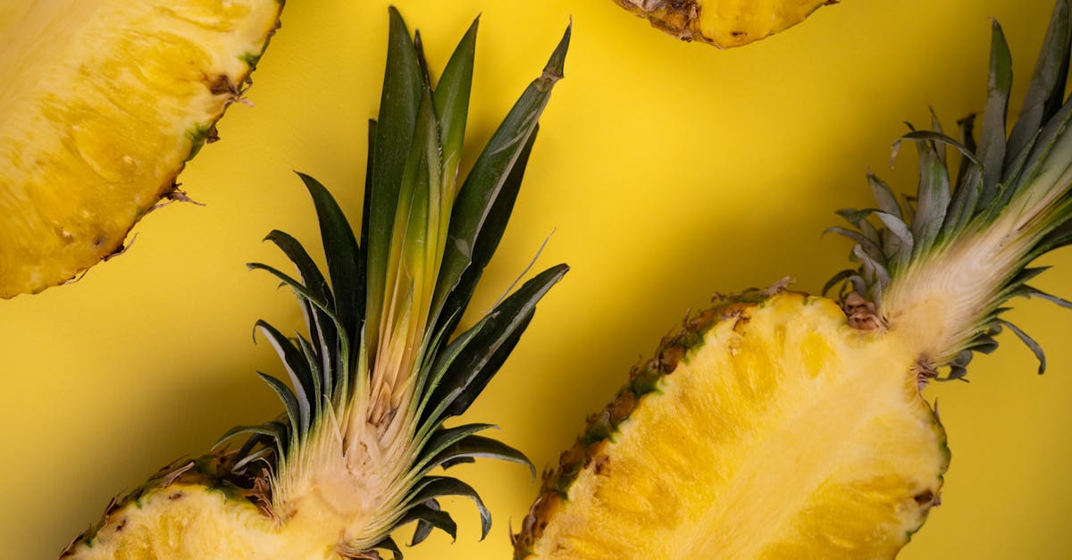 Overhead view of yummy cut pineapples with sweet flesh and wavy leaves on yellow background