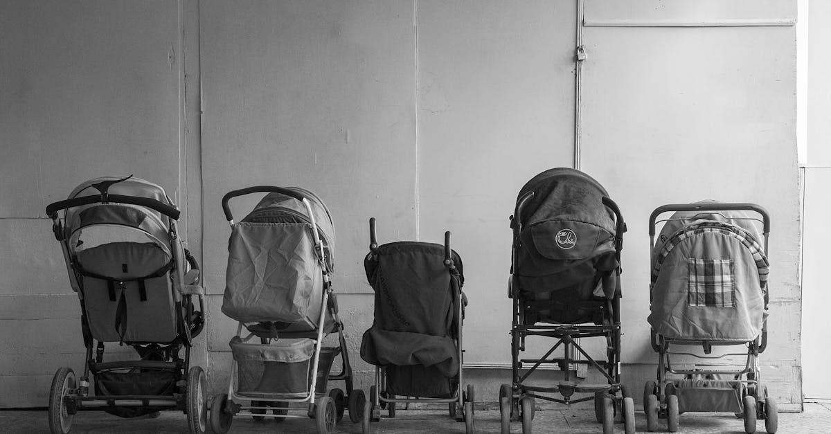 Old baby carriages placed in row near wall in hallway of aged residential building