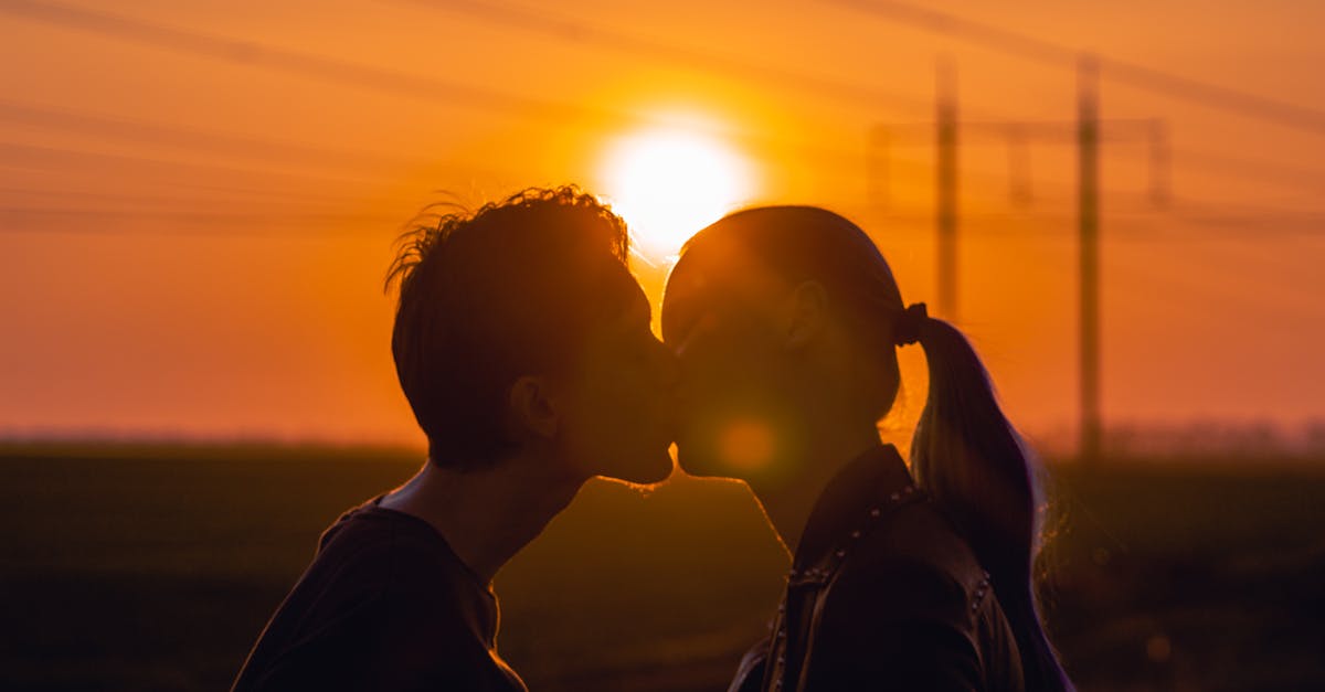 A silhouette of a couple kissing at sunset, capturing romance and affection.