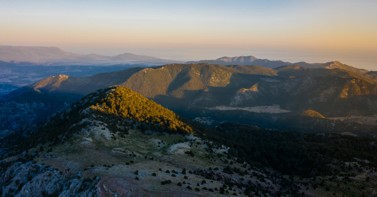 Serene aerial shot capturing the vast mountain landscape under a warm evening sky.