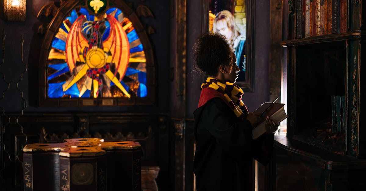 A person dressed in wizard attire stands by books under a vibrant stained glass window in a fantasy setting.
