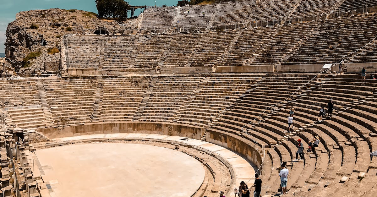 Tourists explore an ancient amphitheater on a sunny day, showcasing historical architecture.