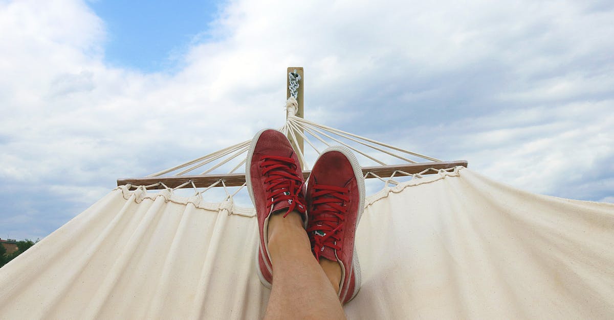 Feet resting on a hammock with red sneakers, epitomizing summer relaxation and leisure outdoors.