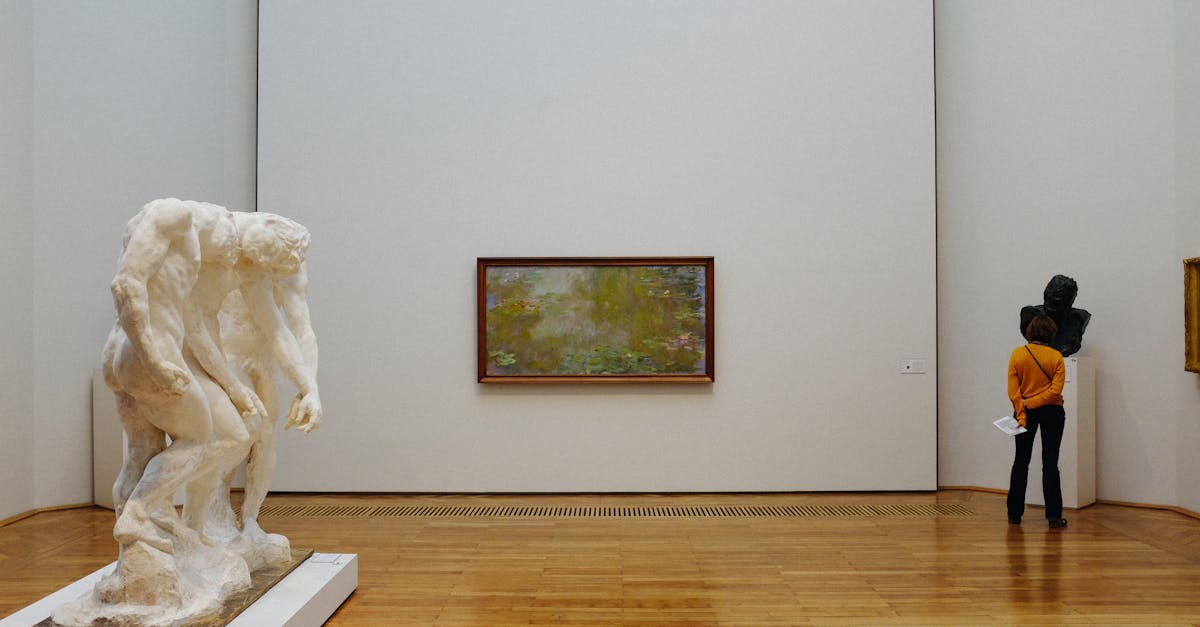 A visitor examines sculptures and paintings at an art museum.