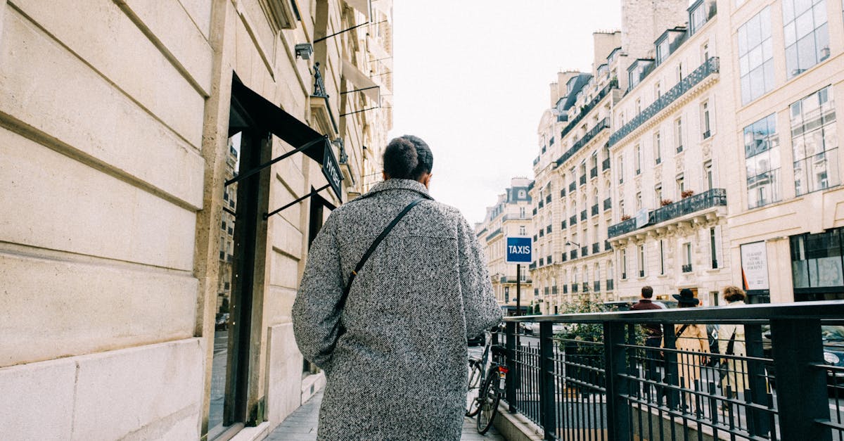 Man wearing coat strolls down a Paris street, capturing urban solitude on a winter day.
