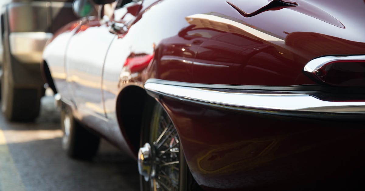 Close-up of a classic Jaguar XK E coupe with shiny chrome details parked in an urban setting.