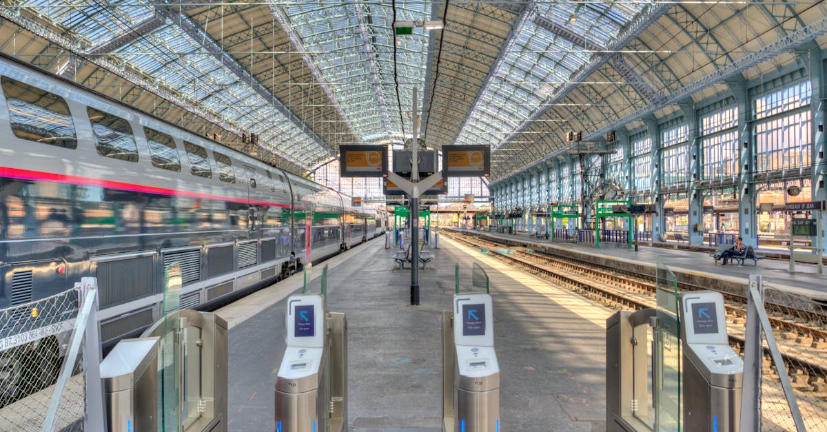 Wide-angle view of a modern train station platform with a parked train under a glass roof.